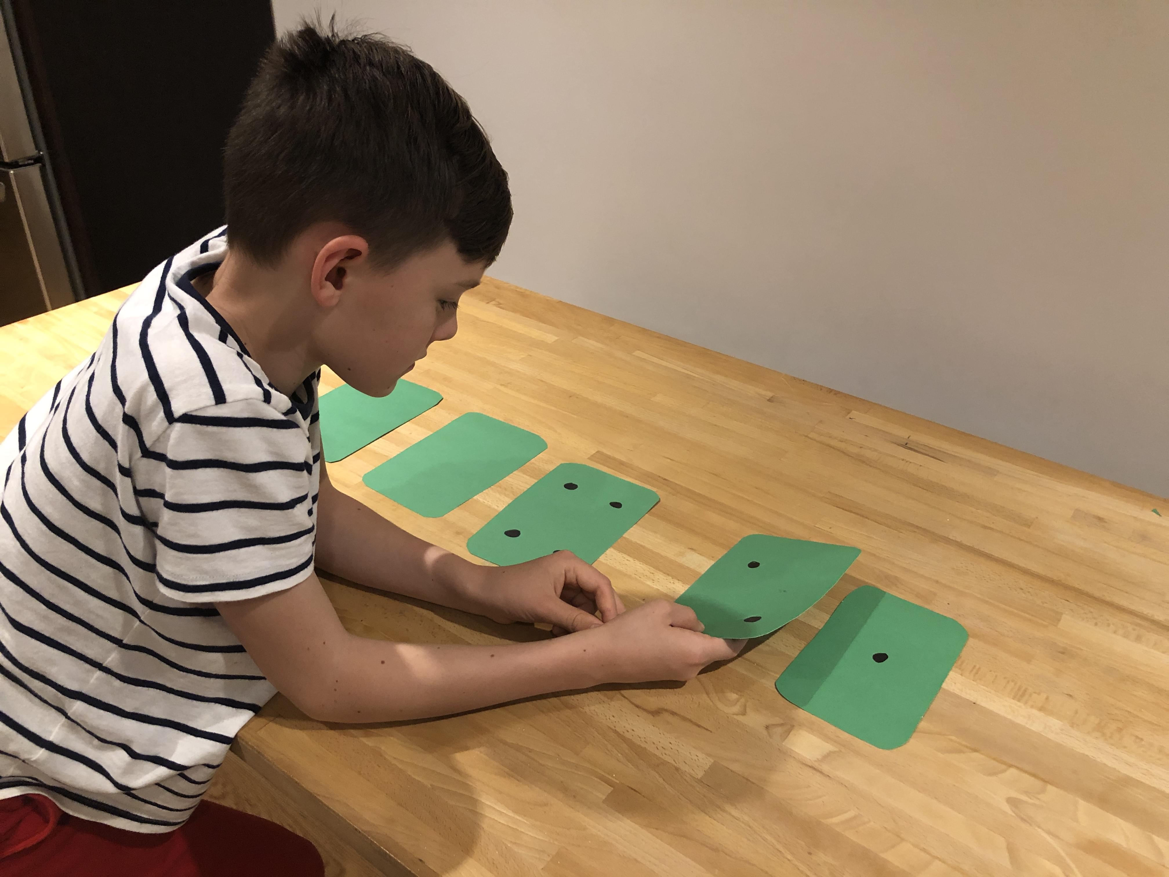 Child flipping over some cards so that five dots are showing.